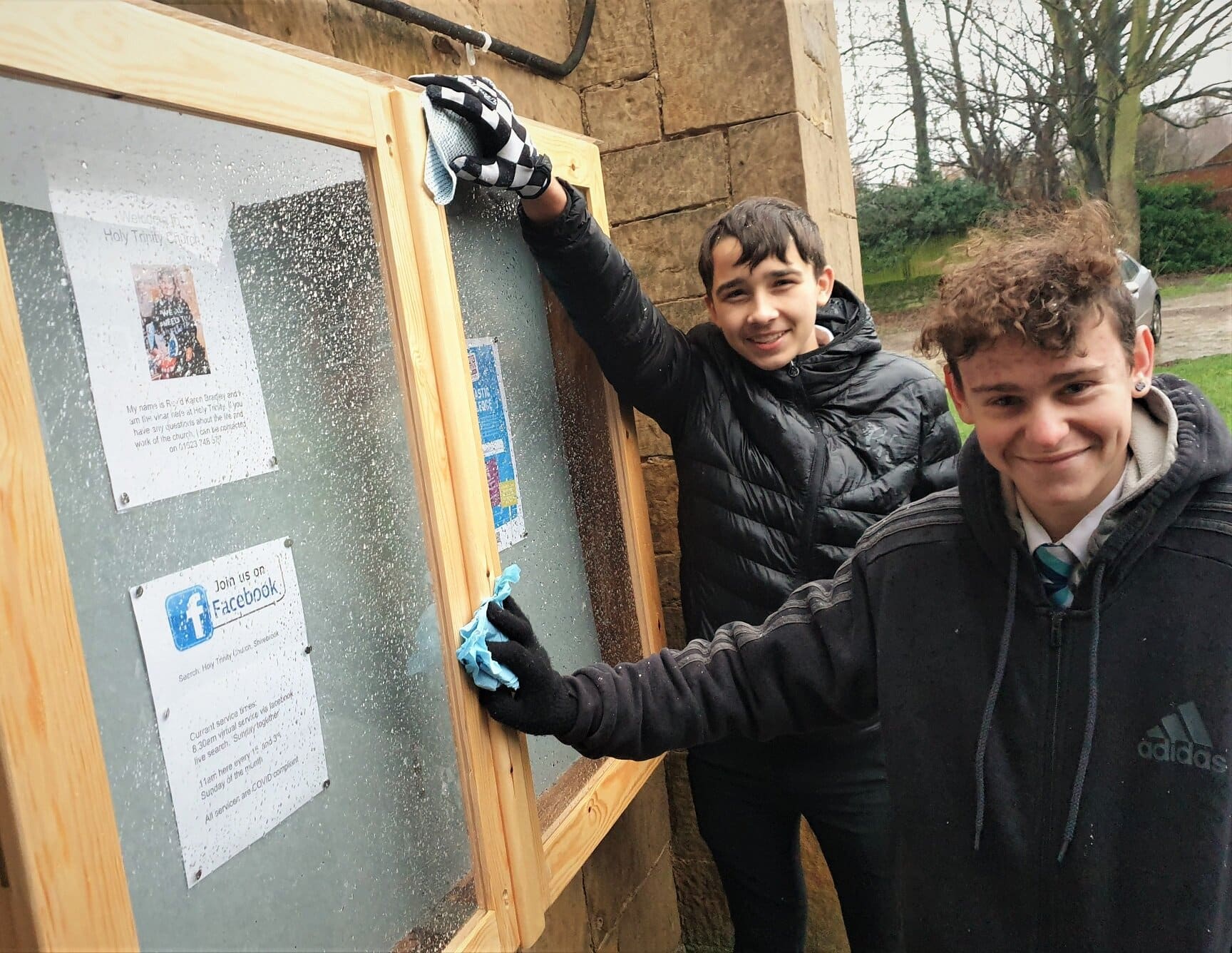 Shirebrook Academy student Nathan Buckingham (left) and Ethan Poole give Holy Trinity Church’s new noticeboard a final wipe-down after he and his classmates made it in their design and technology classes.