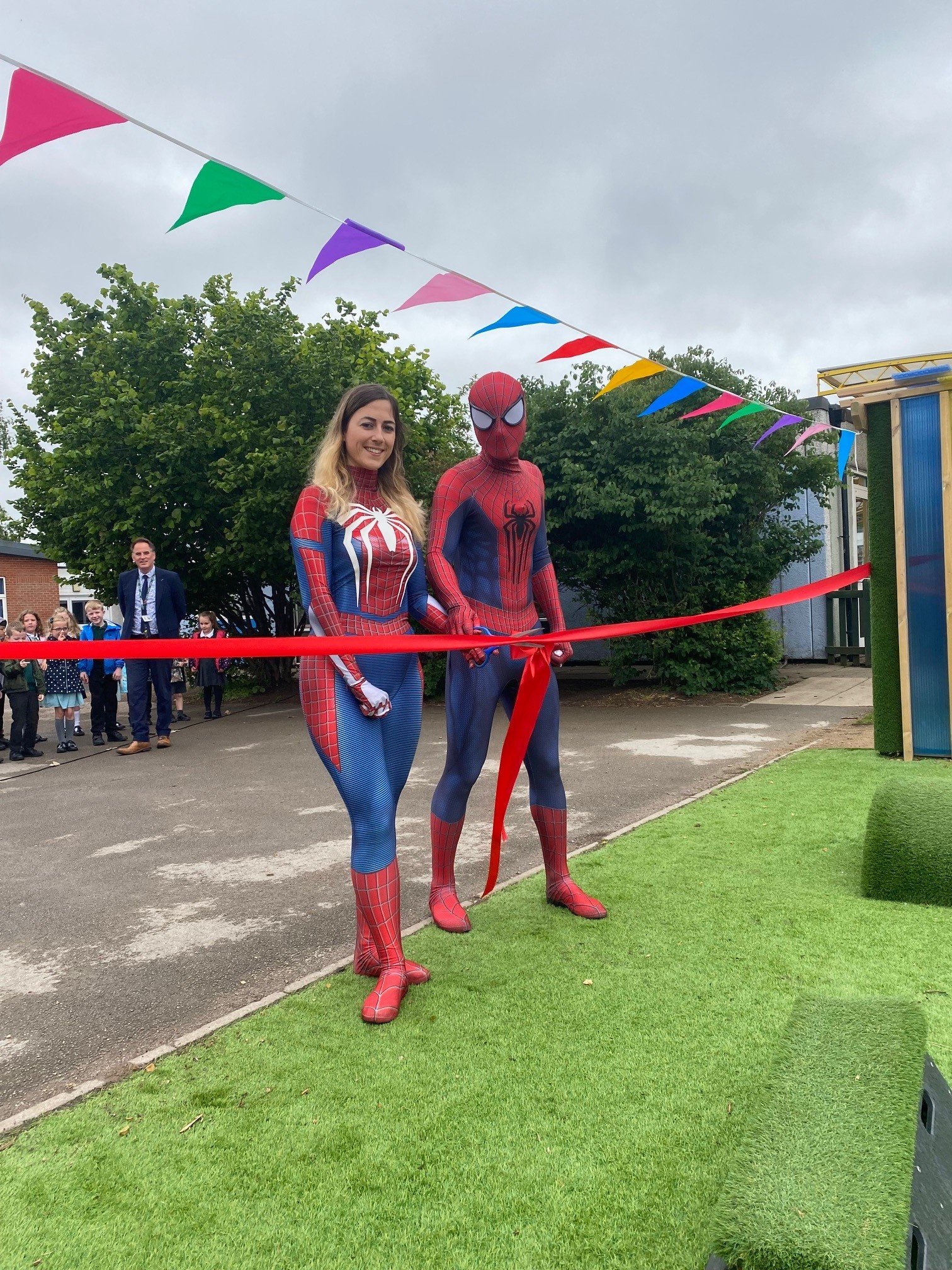 Spider Man and Spider Woman cutting the ribbon to open the garden.