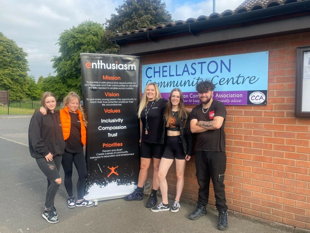 A group of youths outside a community centre with advertisement for a youth club