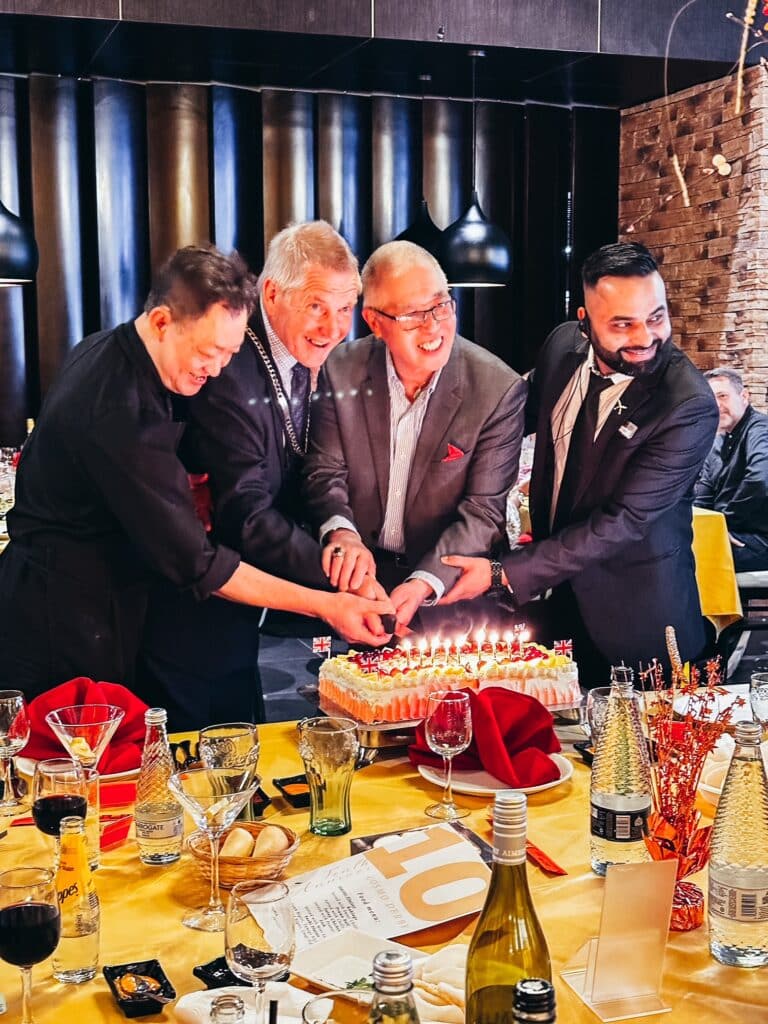 Four men cutting a birthday cake in celebration