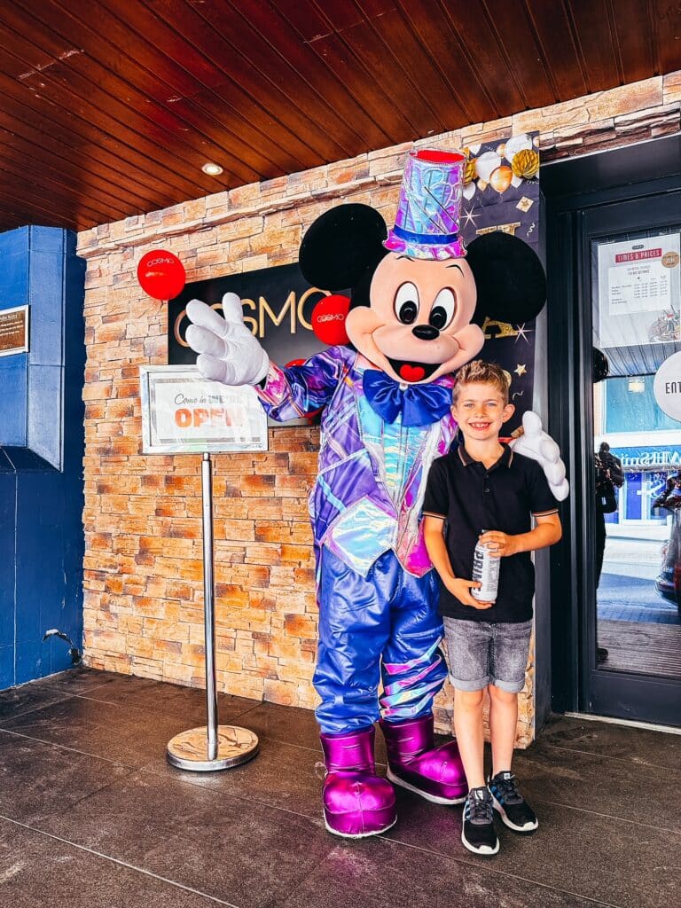 Young boy standing in front of restaurant with Mickey Mouse