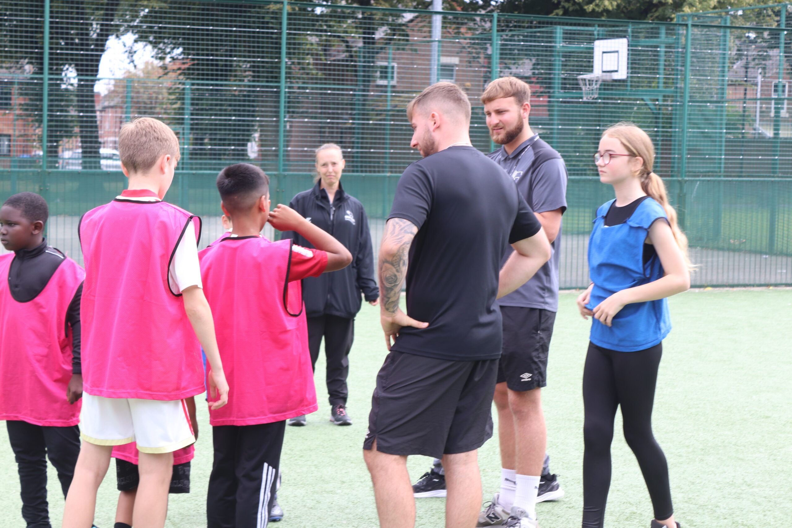 Happy children playing football with Derby County Community Trust coaches