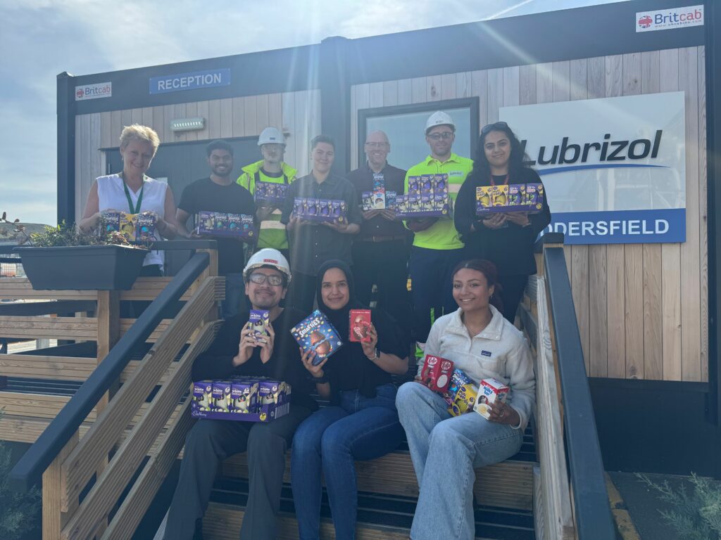photo shows a group of employees from Huddersfield Lubrizol employees holding Easter eggs which were donated to Forget-me-Not Hospice 