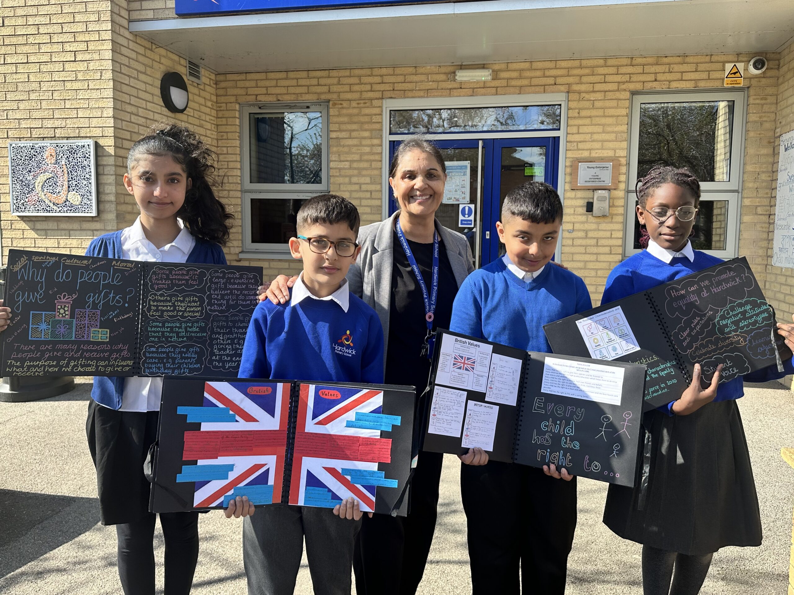 Image shows Mrs Sandhu (centre) with pupils showing their Spritual, Moral, Social and Cultural folders.