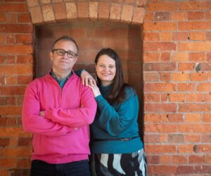 picture of Q Branch founders Matt and Jenny in front of a brick wall