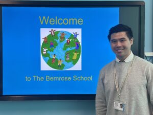 Leo Chan who is a teacher at Bemrose School standing infront of the interactive whiteboard that is depicting a logo