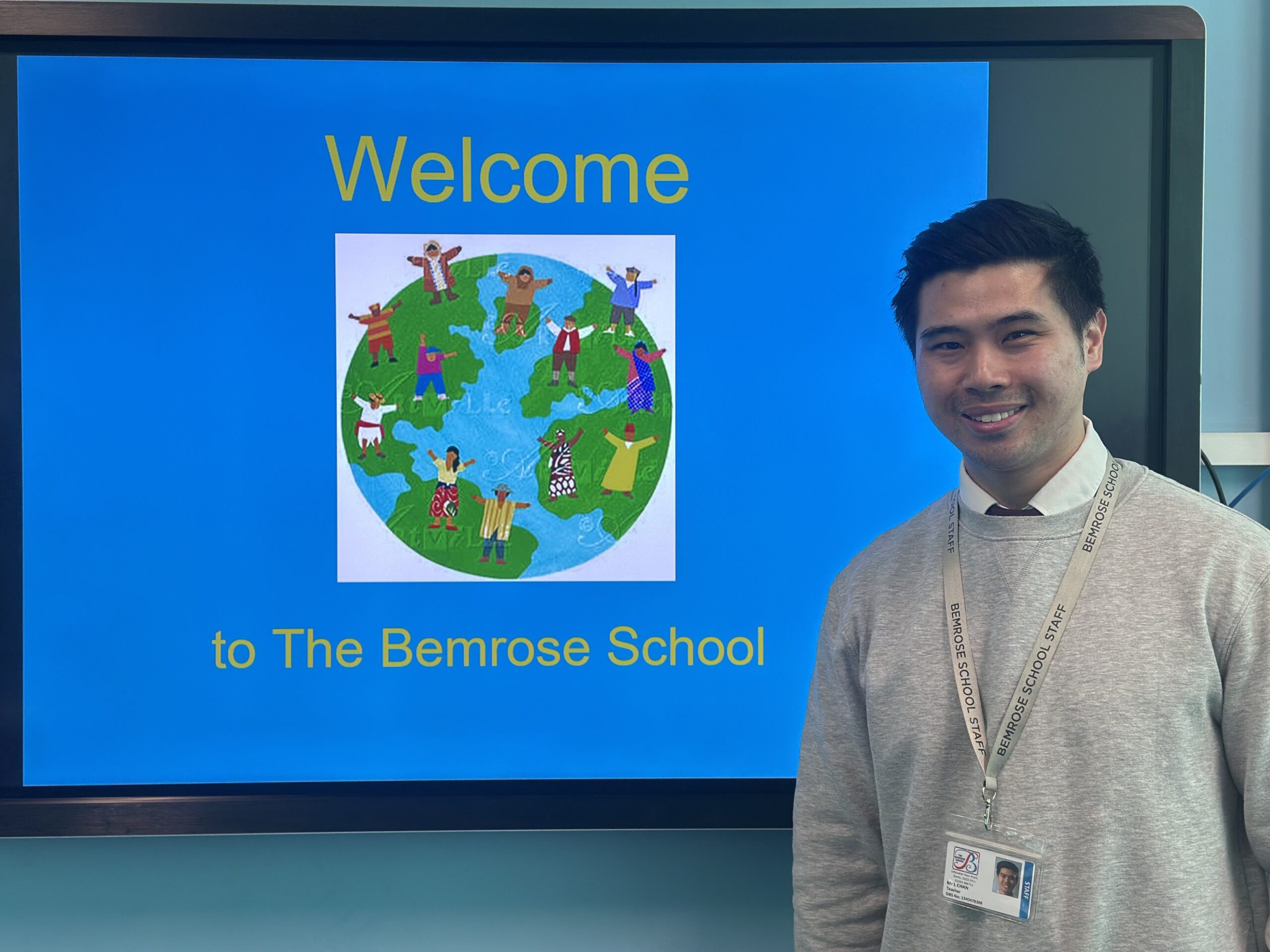 Leo Chan who is a teacher at Bemrose School standing infront of the interactive whiteboard that is depicting a logo