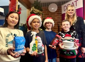 Pupils at Sale & Davys CE Primary School hold up practical items donated by families to support young people from the YMCA move into their own independent accommodation.