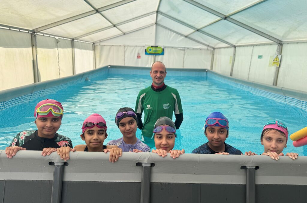 Aisha, Fatima Noor, Aliza, Maryam, Aysa and Henrietta with Wayne Cummings at Arboretum Primary School's pop-up swimming pool.
