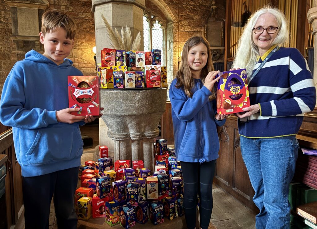 Harry and Amelia, head boy and girl at Norbury C of E Primary School, hand over more than 100 Easter eggs to Jackie Carpenter, assistant director of strategy at Derventio Housing Trust.