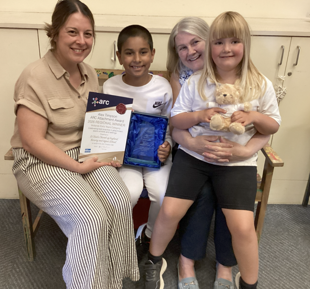 Two pupils from St Chad's CofE Nursery and Infant School sit with two members of staff, proudly displaying the school's ARC Alex Timpson Attachment and Trauma Award after being named the East Midlands regional winner.