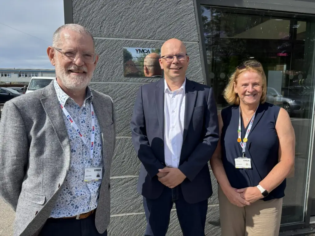 Julian Smith, Matt Jones and Gillian Sewell stand outside a YMCA Derbyshire building, smiling for the camera.
